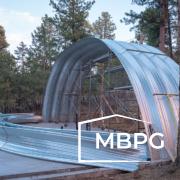 Steel Arch Building Under Construction in a Wooded Area